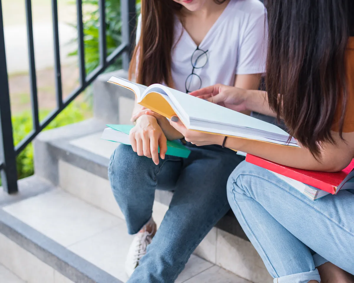 Two students reading together on a set of steps