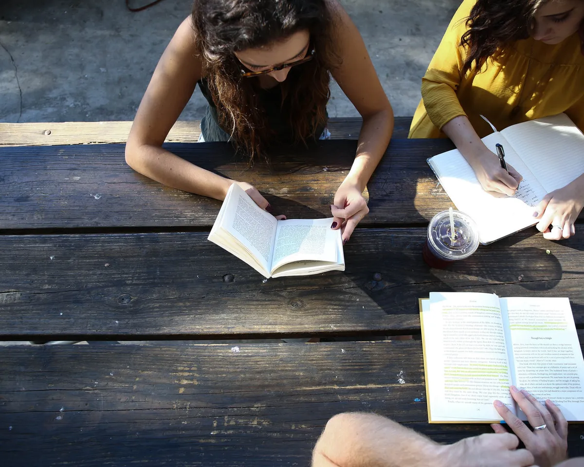 Students working through books at a table